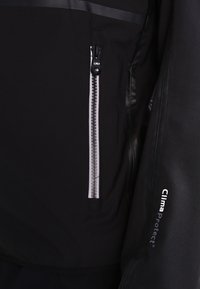 Veste noire avec une poche avant zippée, dotée d'une fermeture éclair grise. Le matériau semble lisse avec un accent brillant, étiqueté "ClimaProtect."