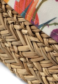 Panier de rangement tissé en matériau de fibre naturelle brun, avec un bord en tissu à motif floral aux couleurs vives.