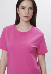 Kortærmet pink T-shirt lavet af bomuld, med rund halsudskæring og glat tekstur, uden synlige mønstre eller accenter.