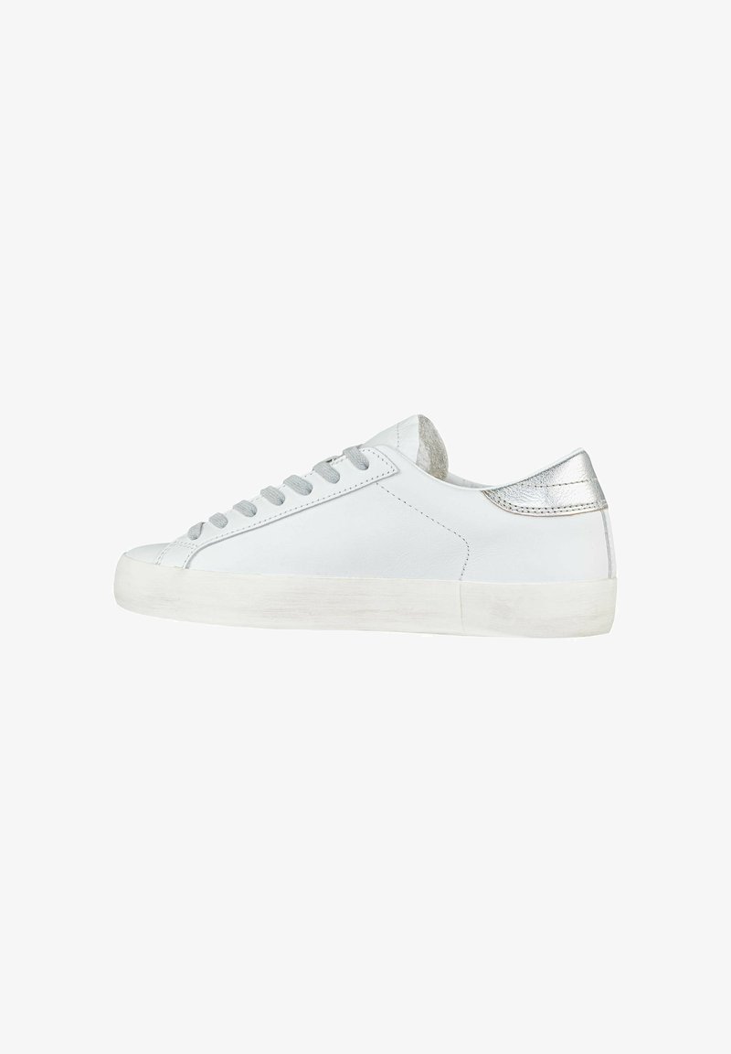 Baskets en cuir blanc avec une texture lisse, bout rond, lacets gris clair et accent argenté sur le talon. Semelle en caoutchouc légèrement vieillie.
