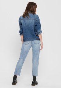 Light blue denim jacket with rolled sleeves and classic collar, paired with light blue straight-leg jeans and black ankle boots.