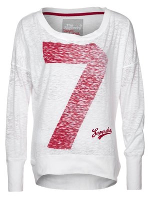 Hvid langærmet skjorte med stort rødt nummer 7 og "Superdry" logo på forsiden, med bred halsudskæring og let gennemsigtigt stof.