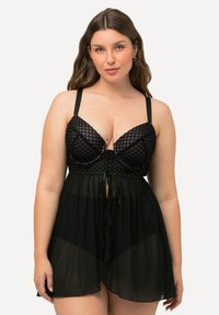 Zwart kanten lingerieset met een geometrisch patroon, doorschijnende rok, verstelbare bandjes en een getailleerde taille met een lintdetail.