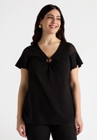 Top negru cu mâneci scurte în stil fluture, decolteu în formă de V și un detaliu central în formă de cerc. Realizat dintr-un material neted, proiectat pentru o croială lejeră.