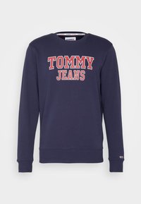 Navy blue sweatshirt featuring bold "TOMMY JEANS" text in red and white, ribbed cuffs, and a round neckline. Made from a soft fabric.