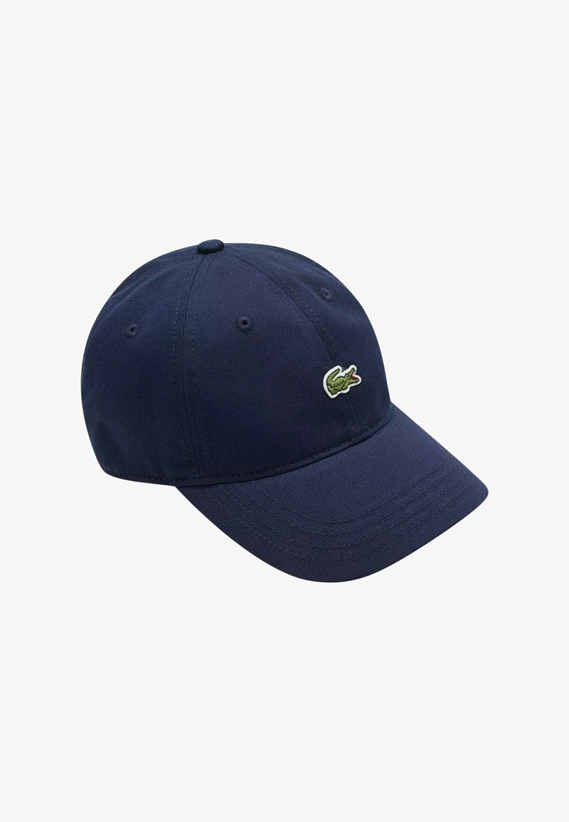 Cappellino da baseball blu navy in tessuto con visiera curva, con un piccolo logo di coccodrillo verde sul davanti. Design e texture classici.