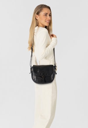 Schwarze Leder-Crossbody-Tasche mit runder Form, Klappe auf der Vorderseite, dekorativem Riemenverschluss und verstellbarem Schulterriemen. Glatte Textur.