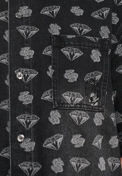 Black denim shirt featuring a repeated grey diamond and skull pattern, with a chest pocket and silver metal button detailing.