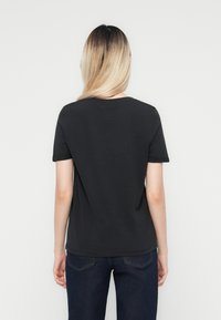Zwart kortemouw t-shirt met een ronde hals en een relaxte pasvorm, gemaakt van zacht katoen. Afgewerkte zomen en opgerolde mouwen.