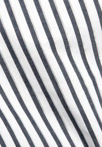 Tessuto con strisce diagonali blu navy e bianche dal tocco morbido. Il tessuto è tessuto, mostrando un motivo uniforme su tutta la sua superficie.