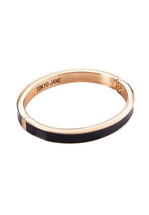 Goldfarbener Armreif mit einer glatten schwarzen Emaille-Einlage. Elegantes, kreisförmiges Design mit einer Scharnierverriegelung und einem eingravierten Logo im Innenbereich.