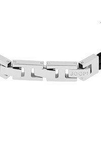 Bracciale metallico con anelli d'argento intrecciati dal design rettangolare e dettagli incisi "JOOP!" su un anello, posizionato su un cinturino in pelle nera.