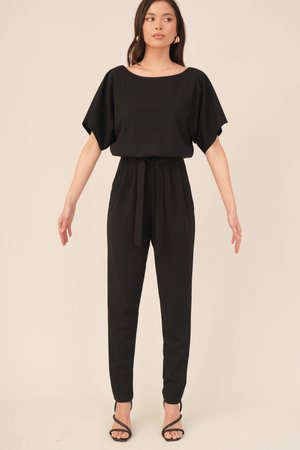 Sort jumpsuit med brede ærmer, indsnævret talje og lige ben. Glat tekstur, minimalistisk stil og bælte detalje ved taljen.