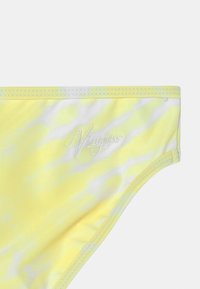 Parte de baixo de bikini amarela com efeito tie-dye, apresentando uma textura suave, listras brancas e uma brandagem bordada na cintura.