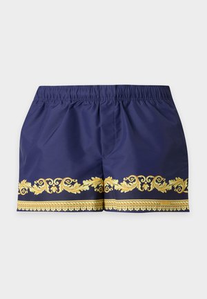 Marineblauwe korte broek met elastische tailleband en een sierlijk gouden barokpatroon langs de onderzoom op een effen lichte achtergrond.