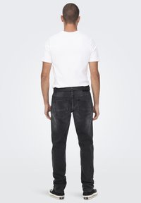 Zwarte spijkerbroek met een rechte pasvorm, met twee achterzakken en een zwarte tailleband. Draag het met een eenvoudig wit t-shirt.