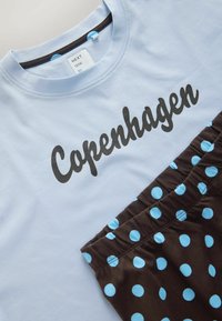 Chemise bleu clair avec le texte "Copenhagen" associée à un short marron avec des pois bleu clair.