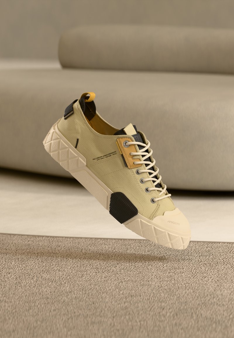 Ανοιχτό πράσινο αθλητικό παπούτσι με μπεζ λαστιχένια μύτη, μαύρες και κίτρινες λεπτομέρειες, υφασμένες κορδόνια και σόλα με γεωμετρικό σχέδιο.