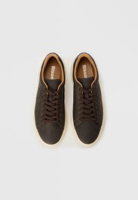 Brown leather sneakers with a smooth finish, brown laces, a beige inner lining, and a white rubber sole. Features a logo on the side.