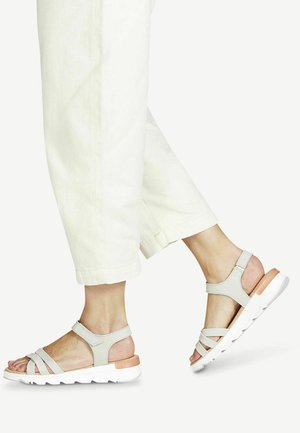 Lys grå sandaler med flere krydsstropper, polstret indersål og en hvid gummisål med en træfiner ved hælen.
