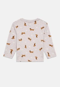 Πουκάμισο με μακριά μανίκια σε ανοιχτό μωβ ύφασμα με σχέδιο σκύλων, που απεικονίζει καφέ και μαύρους σκύλους και μικρά λευκά λουλούδια πάνω σε φόντο με πουά.