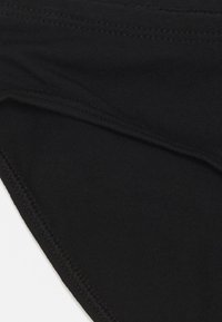 Bikini in cotone nero con una texture liscia, caratterizzato da bordi cuciti e un design senza cuciture. Adatto per l'uso come costume da bagno o come indumento intimo.