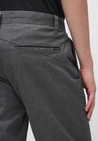 Γκρι παντελόνι από υφασμάτινη υφή, με τσέπη στο πίσω μέρος που φέρει μαύρη ετικέτα Volcom και σχεδιασμό στενής γραμμής.