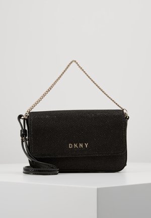 Pochette texturée noire DKNY avec poignée en chaîne dorée et bandoulière amovible en cuir noir sur fond blanc.