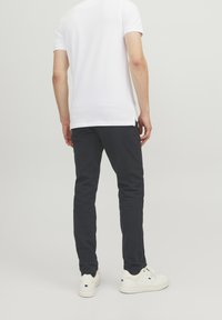 Vit t-shirt med kort ärm kombinerad med mörkblå byxor. Outfiten har en avslappnad passform och minimalistisk design, med vita sneakers.