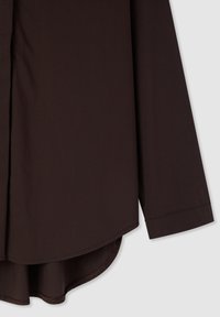 Camicia marrone a maniche lunghe con orlo arrotondato, realizzata in tessuto liscio. Presenta una patta con bottoni e maniche con polsini.