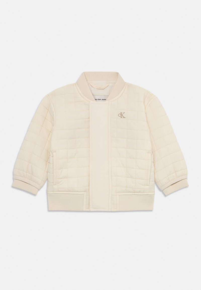Veste matelassée crème avec un col et des poignets côtelés. Comprend une fermeture avant, des poches latérales et un petit logo sur la poitrine.