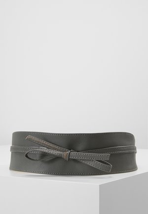 Large ceinture en cuir gris foncé avec un détail de nœud cousu, posée à plat sur une surface blanche avec un fond uni.