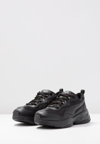 Scarpe da ginnastica nere con un mix di rete e pelle sintetica. Presentano una suola testurizzata, punta arrotondata e lacci per una vestibilità sicura.