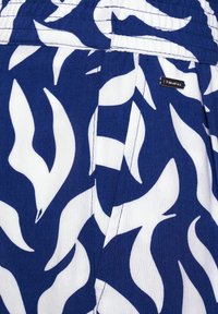 Tmavě modrá látka s bílými vzory připomínajícími plameny. Má pas s elastickým pasem a malou značkovou štítkem přišitým na straně.