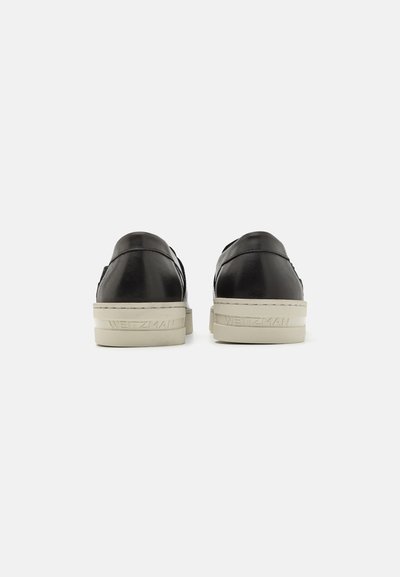 Svarta lädersneakers med låg kläpp och en krämfärgad gummisula, med diskret logotyp på hälen och en stilren, minimal design.