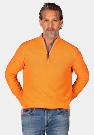 Oranje zip-nekring trui met een gestructureerd patroon, lange mouwen en een relaxte pasvorm, gecombineerd met blauwe spijkerbroeken.