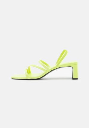 Neonowe żółte sandały na obcasie o minimalistycznym designie, z trzema smukłymi paskami i blokowym obcasem zapewniającym stabilność. Gładka faktura.