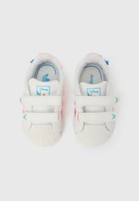 Bielo-ružové detské tenisky s dvoma suchými zipsami, modré motýlikové detaily a logo Disney na jazyku a vnútorných stielkach, zobrazené zhora.