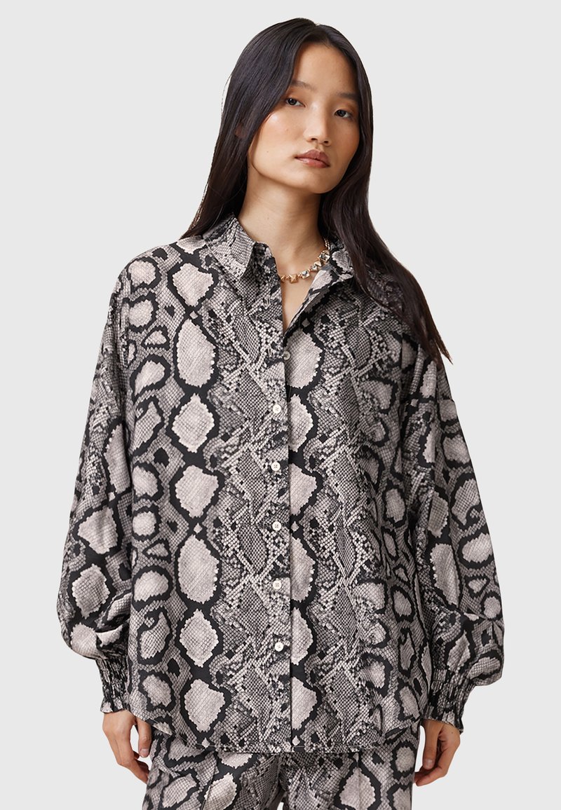 Blusa con stampa a serpente bianco e nero, design con bottoni, vestibilità rilassata, maniche lunghe e polsini elasticizzati, realizzata in tessuto leggero.