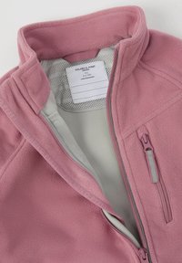 Roze fleecejack met een hoge kraag, ritssluiting aan de voorkant en grijze binnenvoering. Bevat een waslabel dat aan de binnenkant is genaaid. Glad textuur.