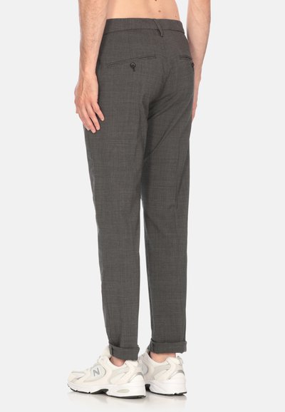 Pantaloni grigi con tessuto testurizzato, taglio slim e risvolti. Presentano due tasche posteriori con bottoni. Abbinati a sneakers bianche.