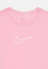 T-shirt Nike Dri-FIT rose avec le logo blanc de la virgule Nike sur la poitrine, un col côtelé et une texture lisse.