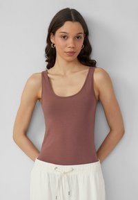 Bruine tanktop met een ronde hals en dunne bandjes. Zachte textuur, aansluitend ontwerp, gecombineerd met een lichte, trekkoordbroek.