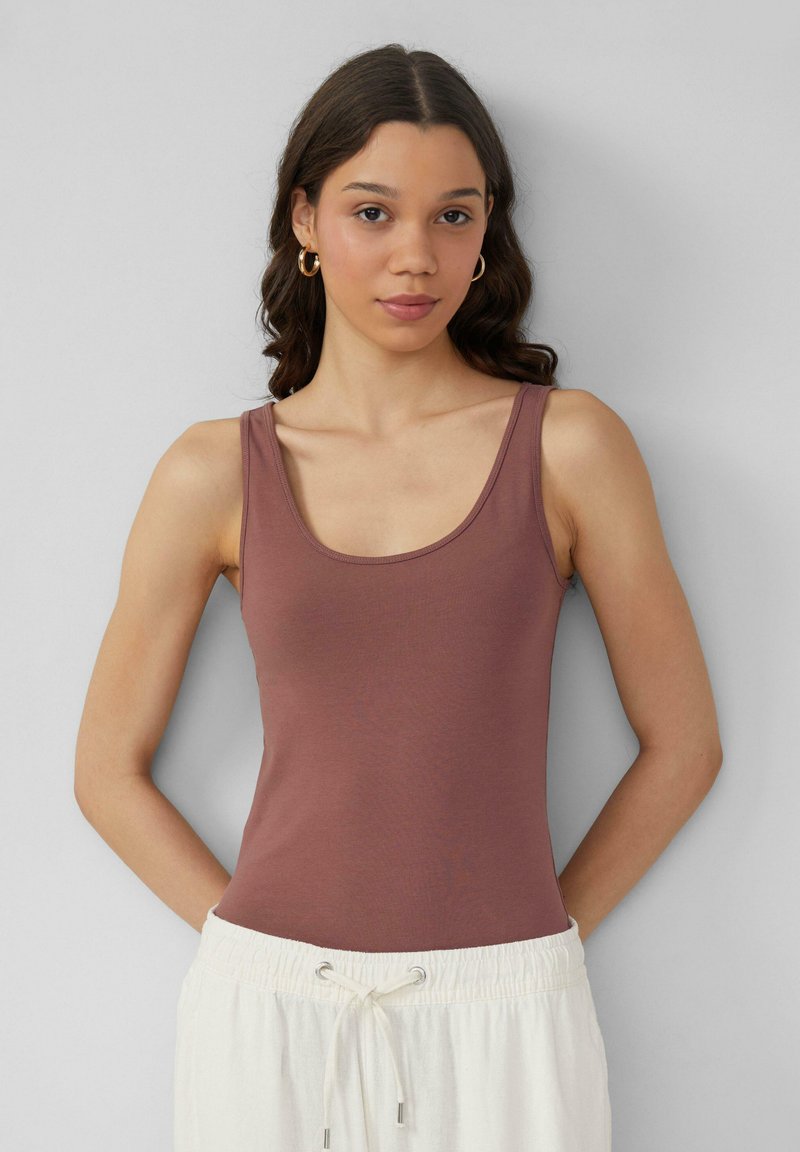 Bruine tanktop met een ronde hals en dunne bandjes. Zachte textuur, aansluitend ontwerp, gecombineerd met een lichte, trekkoordbroek.