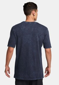 Camiseta de manga corta azul marino con un corte relajado, cuello redondo y una textura ligeramente desgastada. La tela parece suave con un detalle mínimo.