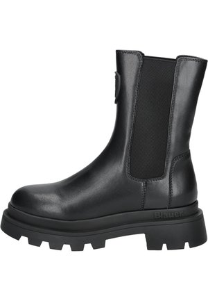 Bottine en cuir noir avec panneau latéral élastique, semelle crantée épaisse et languette à l’arrière, conçue pour un usage décontracté et robuste.