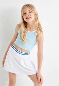 Lysblå ribbet crop top med hvid kant, parret med en hvid skaternederdel med en blåtstribet liv. Glat stof, afslappet design.