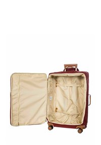 Valise rouge avec un extérieur rigide, doublure intérieure beige, accents bruns et quatre roues. L'intérieur comporte des sangles et une poche zippée.