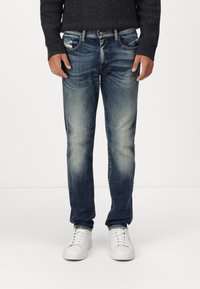Džínsy z denimu s vyblednutou stredne modrou farbou, rovný strih, dizajn s piatimi vreckami a jemné zmiešanie farieb; v kombinácii s bielymi teniskami.