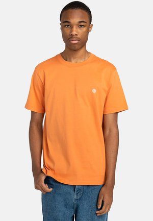 Oranges Baumwoll-T-Shirt mit kurzen Ärmeln, runder Ausschnitt und kleinem Logo auf der linken Brust. Tragen mit blauen Jeans-Shorts.